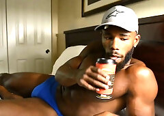 Muscular Black man in blue underwear jerks off while watching porn on laptop