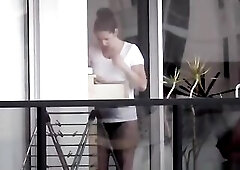 Voyeur secretly spies on his neighbour throughout the window and films her dressing.