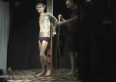 Tattooed submissive endures electrostim under dominant's control in dark chamber