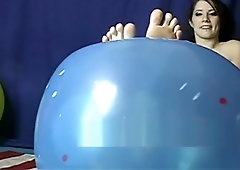 Cute girl pointing her toes and showing her soles playing with balloon