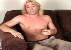 Classy stud with lengthy platinum-blonde hair working on his lollipop