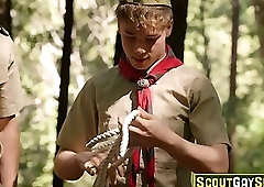 Scout boy tied up against a tree in the woods by two older scout boys
