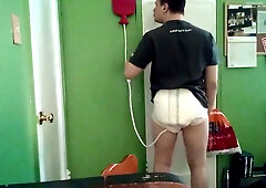 Man prepares an enema in diaper briefs with buttocks exposed in a green room