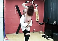 The purple-haired goddess in latex and boots keeps several exposed dudes locked in cages and wooden stocks. That babe tramples, applies clamps and vig
