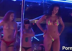 Women in fishnets and bikinis compete in a booty shake contest under neon lights